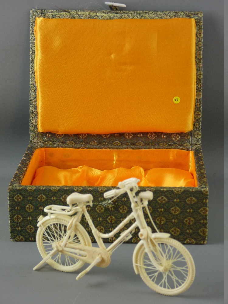 A CHINESE MINIATURE CARVED IVORY BICYCLE, fully reticulated and detailed with folding support stand,