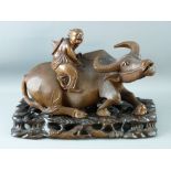 A CHINESE HARDWOOD CARVING on stand in the form of a recumbent water buffalo with a child upon its