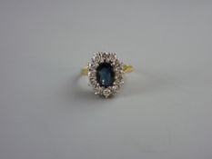 AN EIGHTEEN CARAT GOLD OVAL DRESS RING having a centre oval smoky sapphire with twelve surrounding
