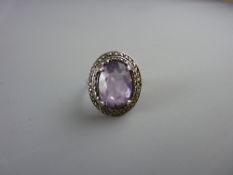 A SILVER DRESS RING with a large oval purple quartz with surrounding tiny marcasites, 6 grms total