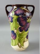 A MOORCROFT 'TRIAL' TWIN HANDLED VASE, fruit and vine decoration on a cream and brown ground,
