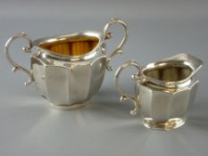AN OVAL SILVER CREAM JUG WITH MATCHING SUGAR BASIN of plain form with panelled bodies and scrolled