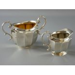 AN OVAL SILVER CREAM JUG WITH MATCHING SUGAR BASIN of plain form with panelled bodies and scrolled