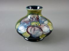 A SMALL MOORCROFT 'CLEMATIS' SQUAT VASE decorated on a tonal green ground, original paper label to