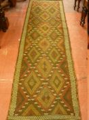 A SUZNI KILIM RUNNER, rust and red ground with repeating multi-diamond central pattern and narrow