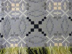 A VINTAGE WELSH WOOLLEN SINGLE BEDSPREAD in lavender, green and black tones