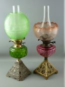 TWO VICTORIAN OIL LAMPS with iron bases, coloured glass reservoirs and fine etched glass shades