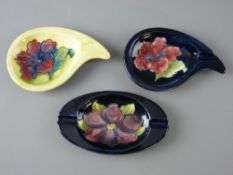 THREE MOORCROFT 'HIBISCUS' & 'CLEMATIS' PATTERNED ASHTRAYS, decorated on cobalt and yellow