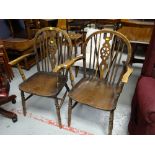 A pair of wooden wheel back elbow chairs