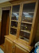 A pine bookcase cupboard with two-door glazed top & brass fittings