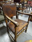 A distressed part leather turned wood elbow chair