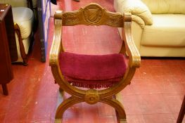 Carved oak 'X' framed armchair, the back rail with crested roundel