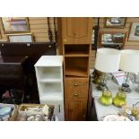 Light wood effect modern narrow cupboard with central drawers and a similar shaped white bathroom