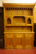 A REPRODUCTION PINE GOTHIC OAK STYLE DRESSER, the castellated top over a decorative canopy frieze,