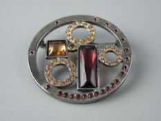 A MODERN WHITE METAL SWAROVSKI CIRCULAR BROOCH with amber and amethyst colour settings in a