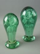TWO VICTORIAN BALLOON SHAPED GREEN GLASS DUMP PAPERWEIGHTS having multi-headed floriate