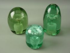 THREE VICTORIAN GREEN GLASS DUMP PAPERWEIGHTS with single flower and pot inclusions, 11 cms high the