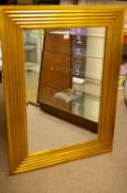 A LARGE REPRODUCTION GILT FRAMED WALL MIRROR of rectangular form with reeded decoration and bevelled