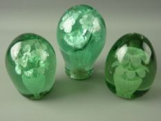 THREE VICTORIAN GREEN GLASS DUMP PAPERWEIGHTS with double flower head in pot inclusions, 10 cms high