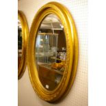 A LARGE REPRODUCTION WALL MIRROR in classically styled oval gilt frame with bevelled edge glass,