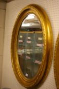 A LARGE REPRODUCTION WALL MIRROR in classically styled oval gilt frame with bevelled edge glass,