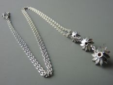 AN EIGHTEEN CARAT WHITE GOLD TRIPLE GRADUATED FLORAL PENDANT, diamond set with fine link chain