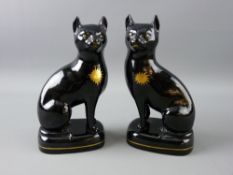 A GOOD PAIR OF JACKFIELD STYLE POTTERY CATS seated on oval bases, the fronts with gilt star