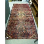 A RED GROUND PERSIAN RUNNER with all over design and central stepped medallion, 264 x 118 cms