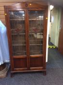 A compact vintage oak display cabinet with leaded coloured glass doors