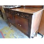 A vintage oak railback sideboard with decorative carving to two drawers above a two cupboard