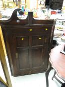 An antique oak hanging corner cupboard with three-shelf interior & small drawer to base (