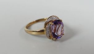 A 9CT YELLOW GOLD AMETHYST & DIAMOND RING the oval amethyst raised over a shaped border of small