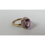 A 9CT YELLOW GOLD AMETHYST & DIAMOND RING the oval amethyst raised over a shaped border of small