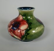 A MOORCROFT GREEN GROUND SQUAT NARROW NECKED VASE with tube-lined flowers, 7cms high