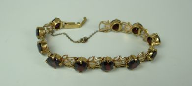 A 9CT YELLOW GOLD SET RED GARNET BRACELET of floral design, 17gms