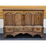 AN EARLY NINETEENTH CENTURY OAK BLANKET CHEST converted to shelved cupboard and having a three