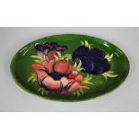 A MOORCROFT OVAL GREEN GROUND DISH with tube-lined flowers, 23cms