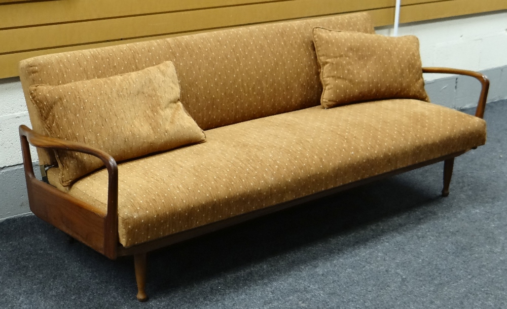 A 1950s GREAVES & THOMAS TEAK DAYBED / SETTEE with open sides & shaped arms raised over turned