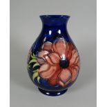 A MOORCROFT BLUE GROUND FLORAL BALUSTER VASE with narrow neck, 18cms high
