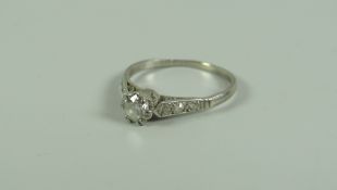 AN ANTIQUE DIAMOND RING with round cut diamond & small diamonds to the shoulders set in white metal