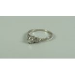 AN ANTIQUE DIAMOND RING with round cut diamond & small diamonds to the shoulders set in white metal