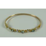 A MODERN BLUE 9k YELLOW GOLD GEMSTONE BANGLE, 5.5gms