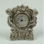 A MINIATURE WHITE METAL, BELIEVED SILVER, CLOCK of Rococo figural form