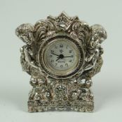 A MINIATURE WHITE METAL, BELIEVED SILVER, CLOCK of Rococo figural form