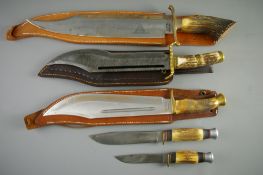 THREE LARGE REPLICA HUNTING KNIVES with leather sheaths and two small Bowie type knives, all with