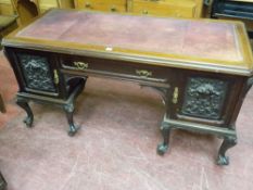 A VICTORIAN CARVED MAHOGANY DESK, Continental in style with gilt tooled red leather top over a