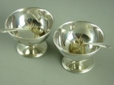 A PAIR OF CIRCULAR SILVER PEDESTAL SALTS & ASSOCIATED SPOONS, Sheffield, 1929 and 1885 respectively,