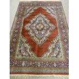 A RUST GROUND EASTERN WOVEN CARPET with spandrel and cartouche decorated centre with a multi-