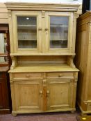 A CONTINENTAL PINE GLAZED TOP DRESSER having carved detail to the front, twin glazed top doors