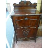 A LATE VICTORIAN MAHOGANY MUSIC CABINET by Maple & Co, the shaped top and back rail with carved